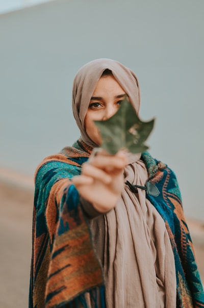 女人拿着绿色的手掌状的有叶子的植物
